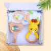 Hello World Baby Gift Set 3 top view with giraffe crochet rattle, fish and bear wooden teethers, and swaddle